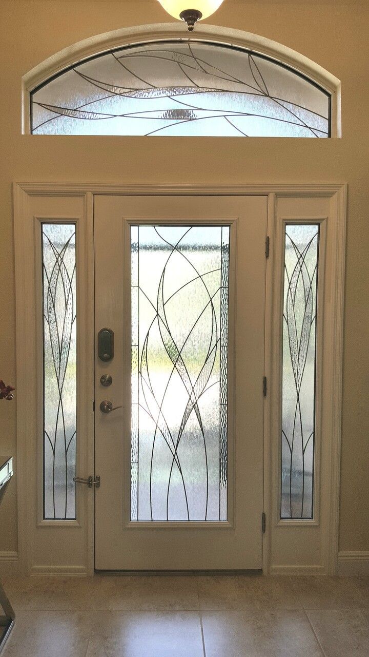 White front door with decorative glass panels and arched transom window.