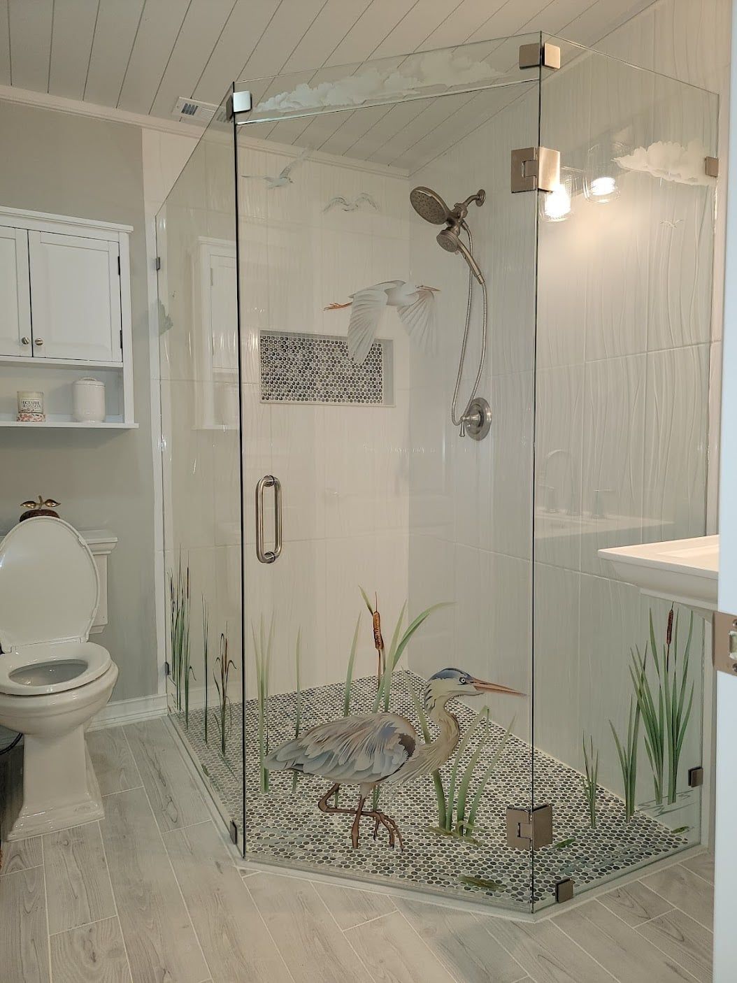 Glass-enclosed bathroom shower with mosaic tile, white fixtures, and a toilet visible beside it