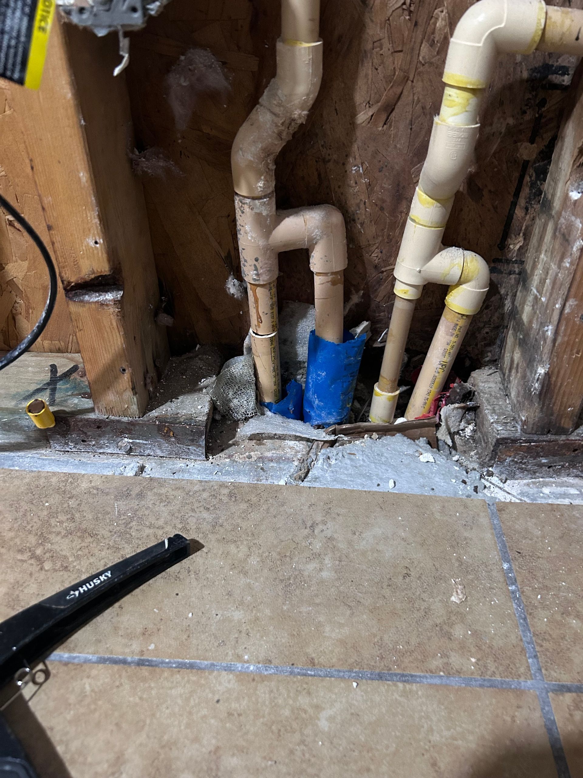 A bunch of pipes are coming out of a hole in the wall.