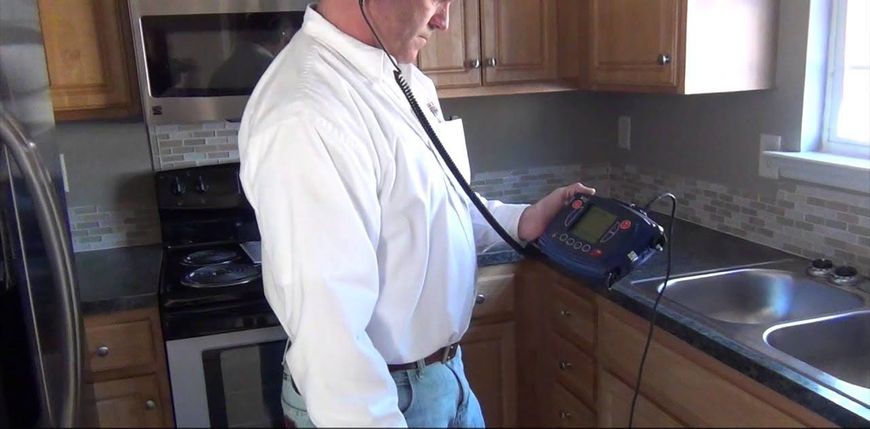 A man in a white shirt is using a stethoscope in a kitchen.