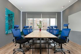 Modern conference room with blue chairs, a long wooden table, and large windows