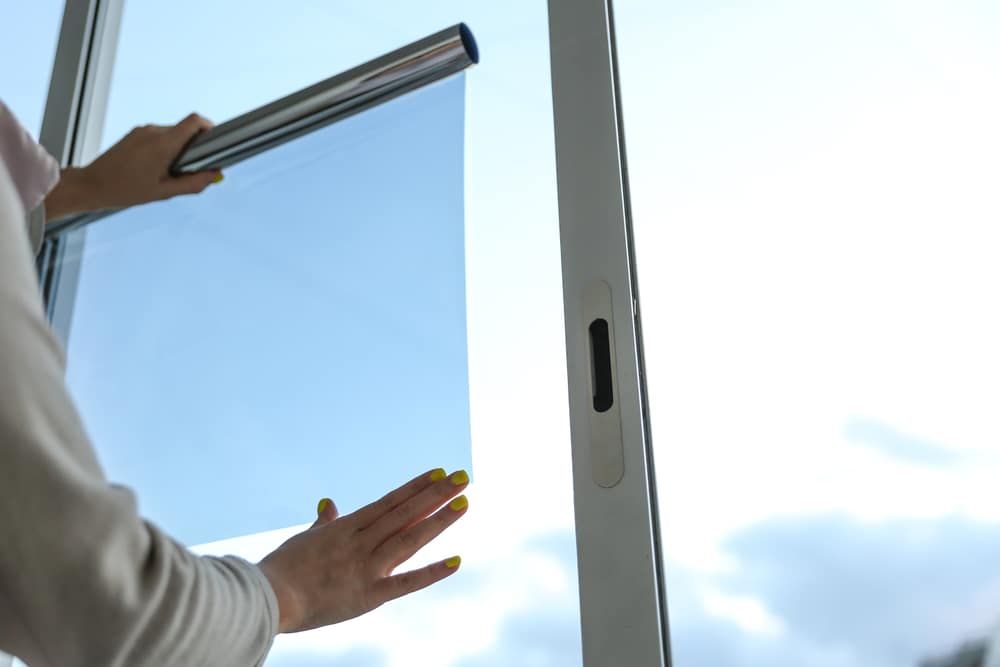 a Woman is Installing a Window Film on a Window — Total Tint Bendigo in East Bendigo, VIC