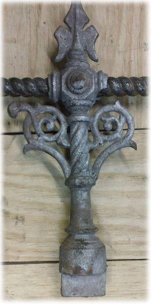 A metal object with a cross on top is sitting on a wooden table.