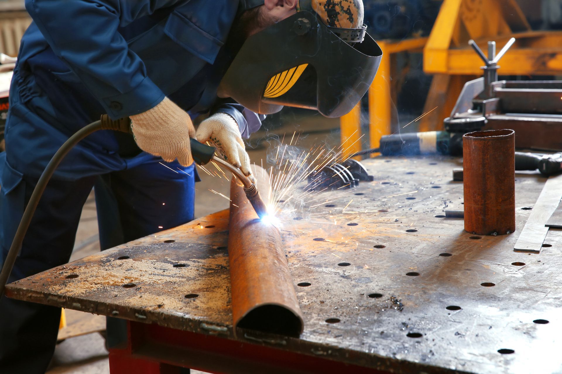 A worker using welding equipment for metalworking in a shop. A worker using welding equipment for metalworking in a shop.