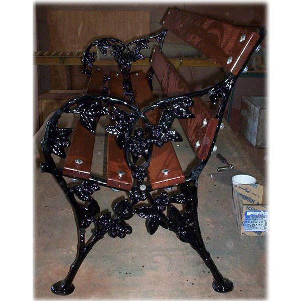 A wooden bench with a black wrought iron frame