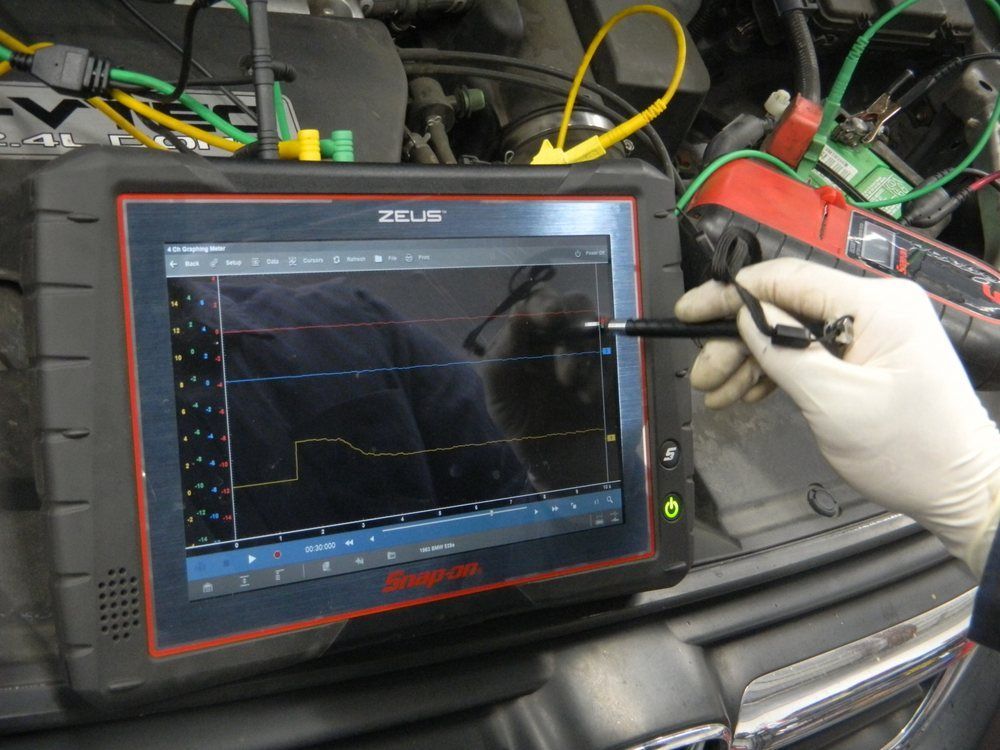 Mechanic uses a diagnostic tool with a touchscreen to analyze engine data.