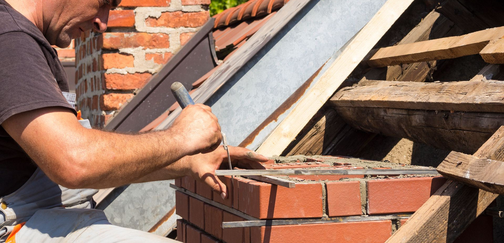A chimney contractor measures the thickness of a line of bricks on a chimney.