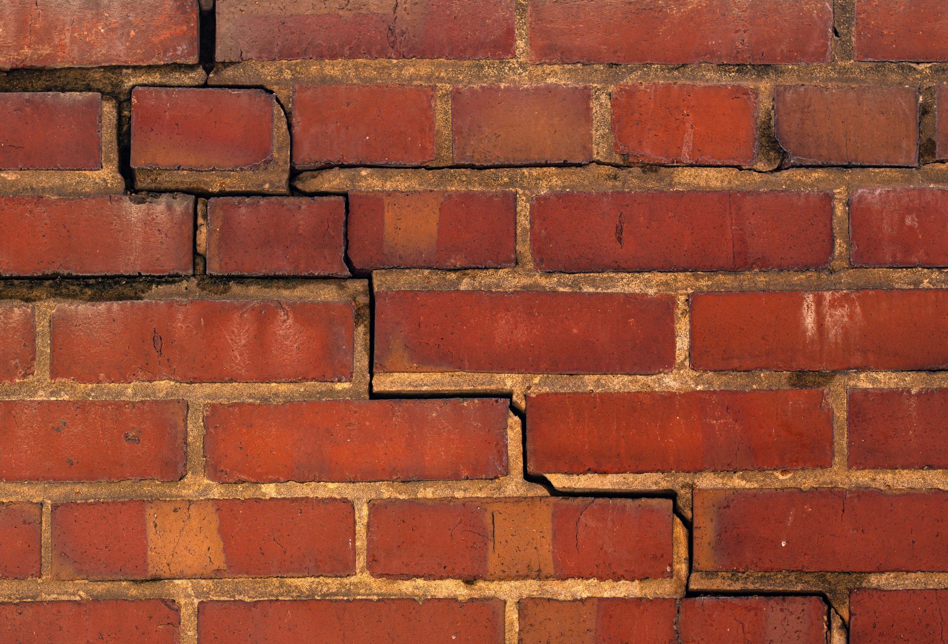 Red brick wall with a stepped pattern of shifted bricks across the center Red brick wall with a stepped pattern of shifted bricks across the center
