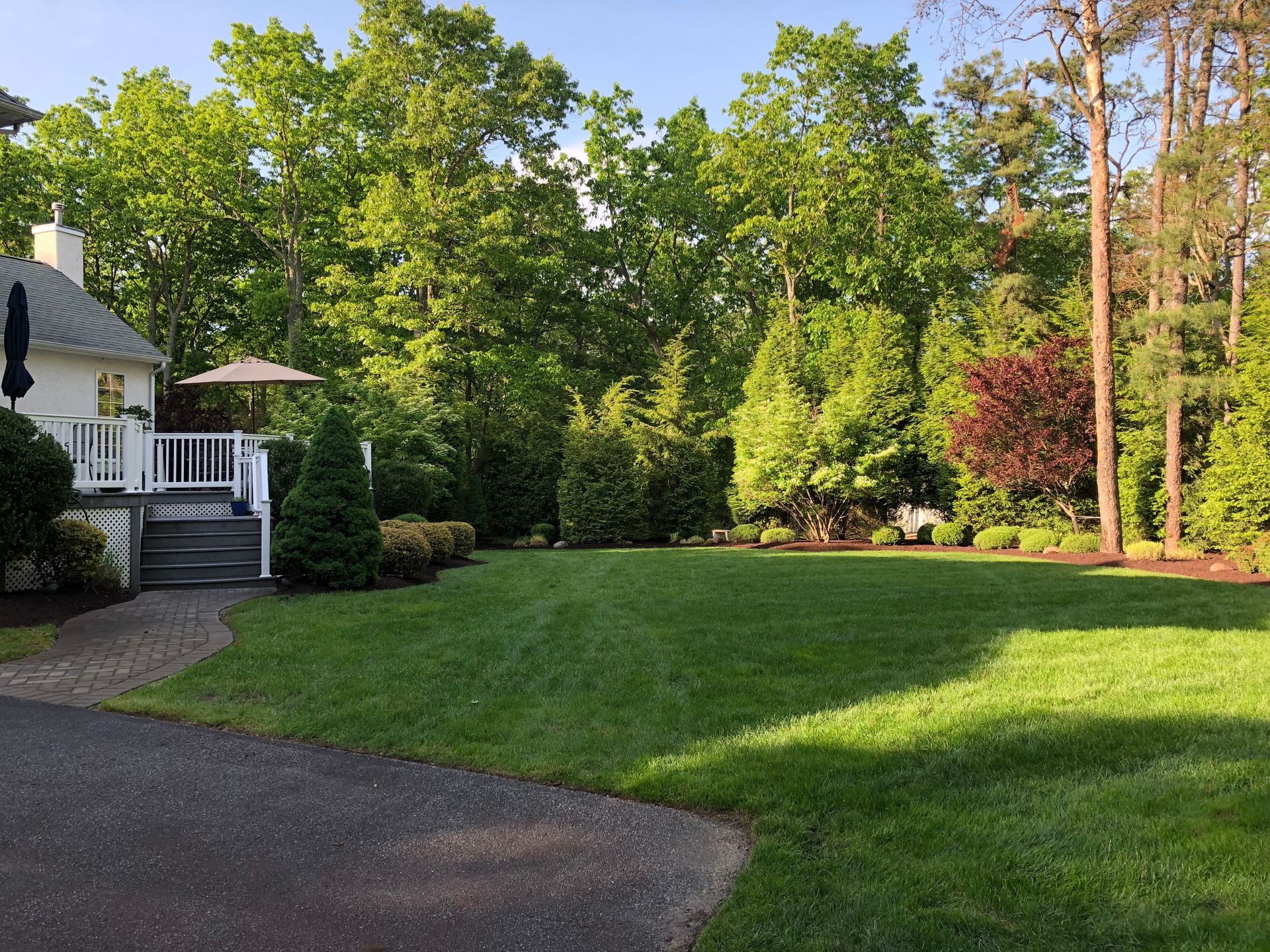 Gardener in blue tending flower beds in a manicured park with hedges and winding paths