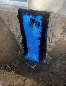 Patch mural bleu étanche avec bordure noire sur un mur de fondation extérieur
