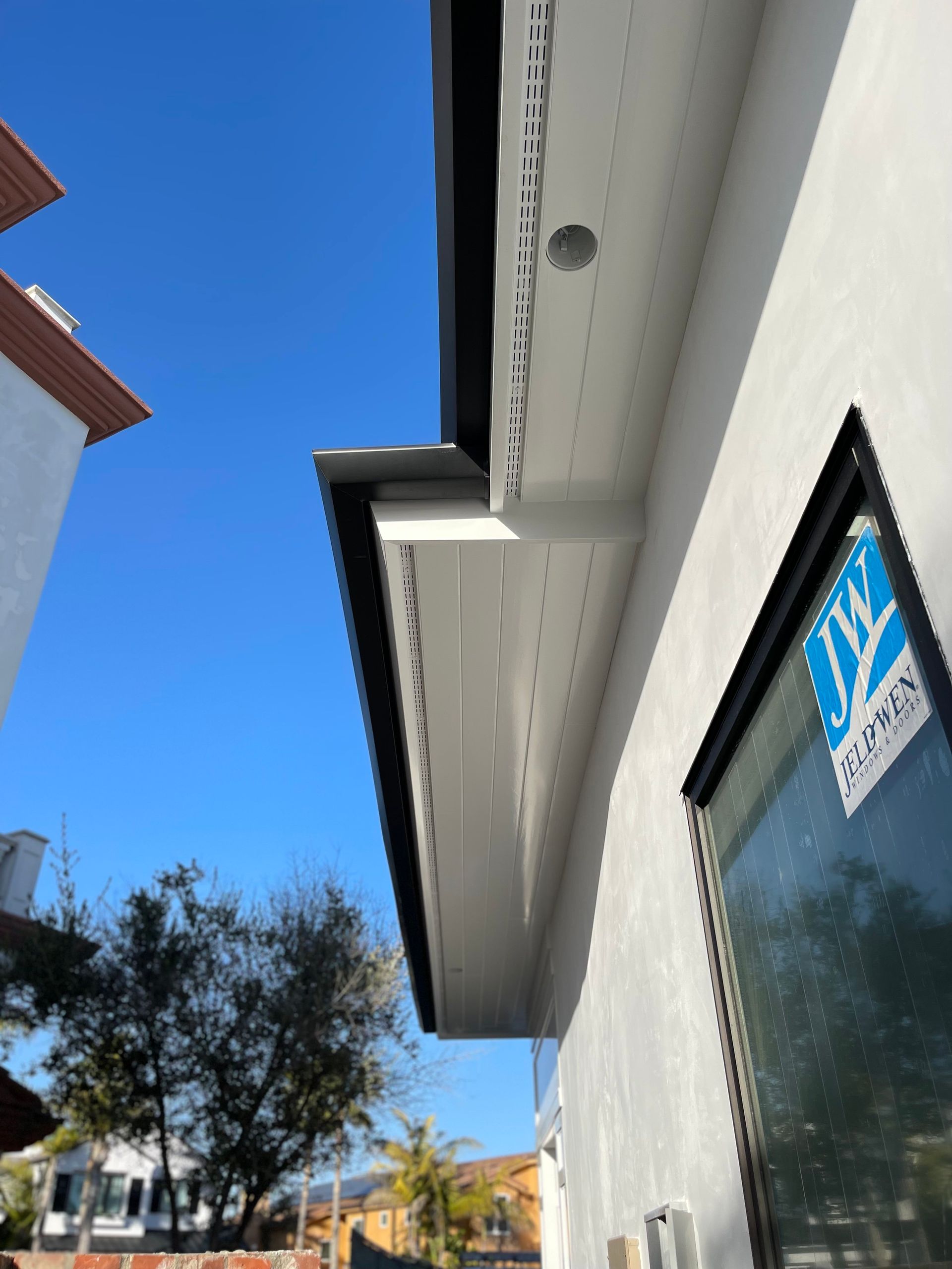 Exterior view of a modern white building with black trim, a blue sky is visible in the background.