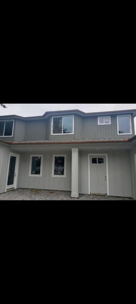 Two-story house with light gray stucco exterior and white trim, windows, and door.