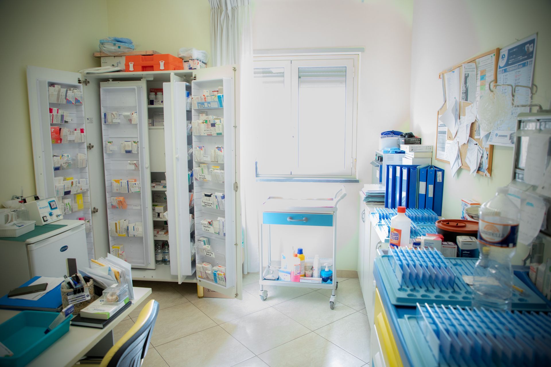 Un ambulatorio medico ben fornito, con armadietti, carrello, finestra e forniture.