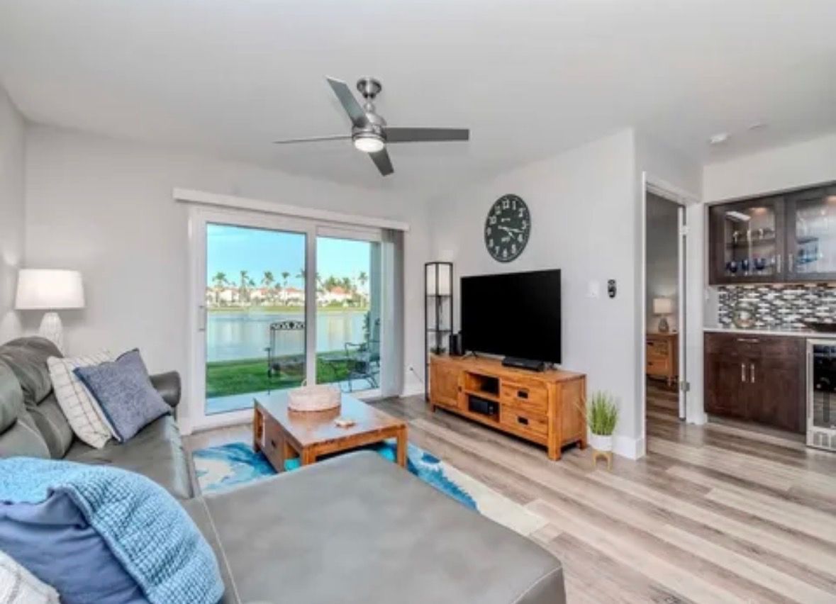 Bright living room with gray sectional, TV console, coffee table, and sliding doors to a patio.