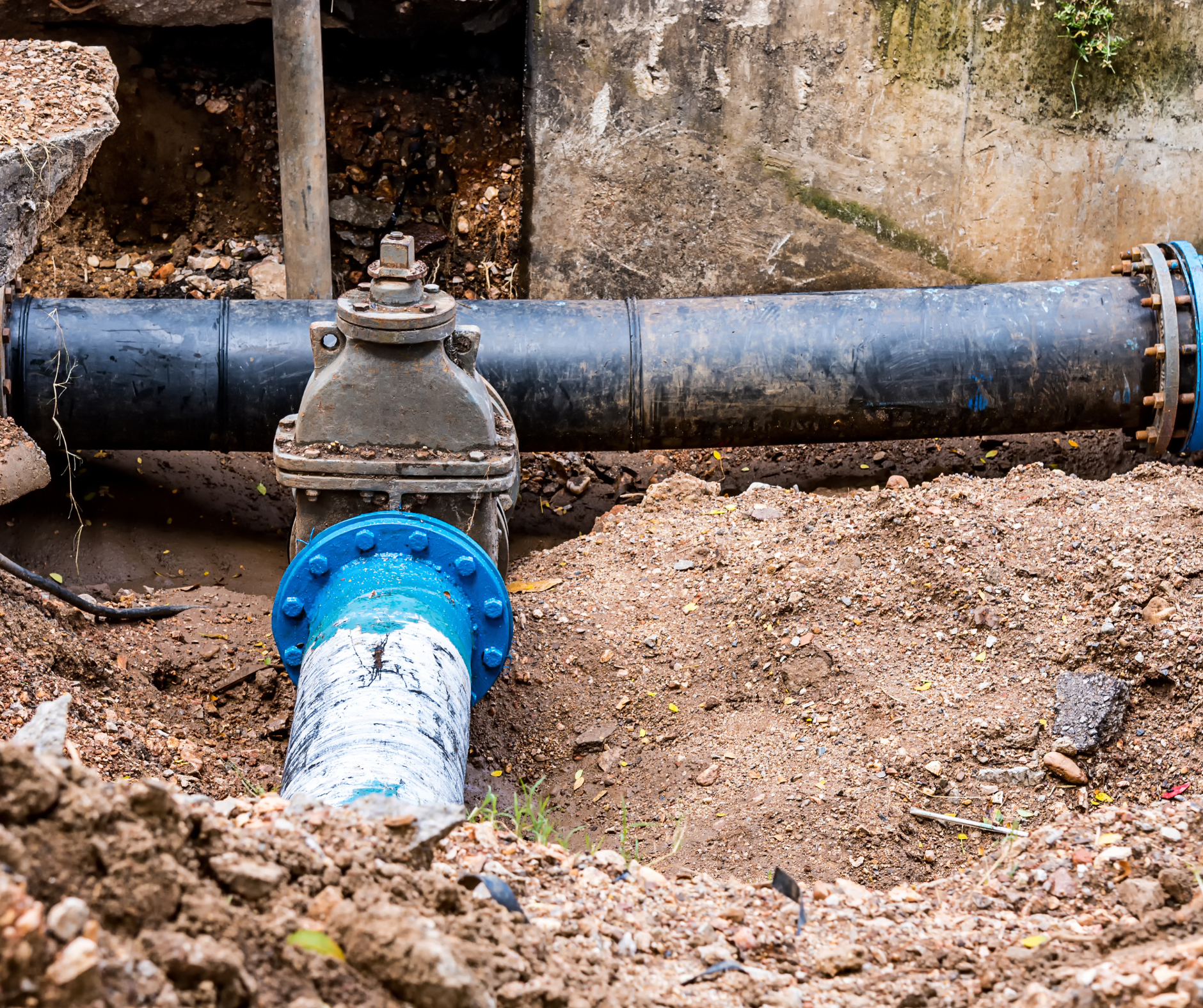 Large blue and black water pipes with valve, installed underground.