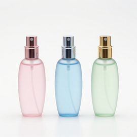 Tres botellas de spray de colores pastel en rosa, azul y verde sobre un fondo blanco.