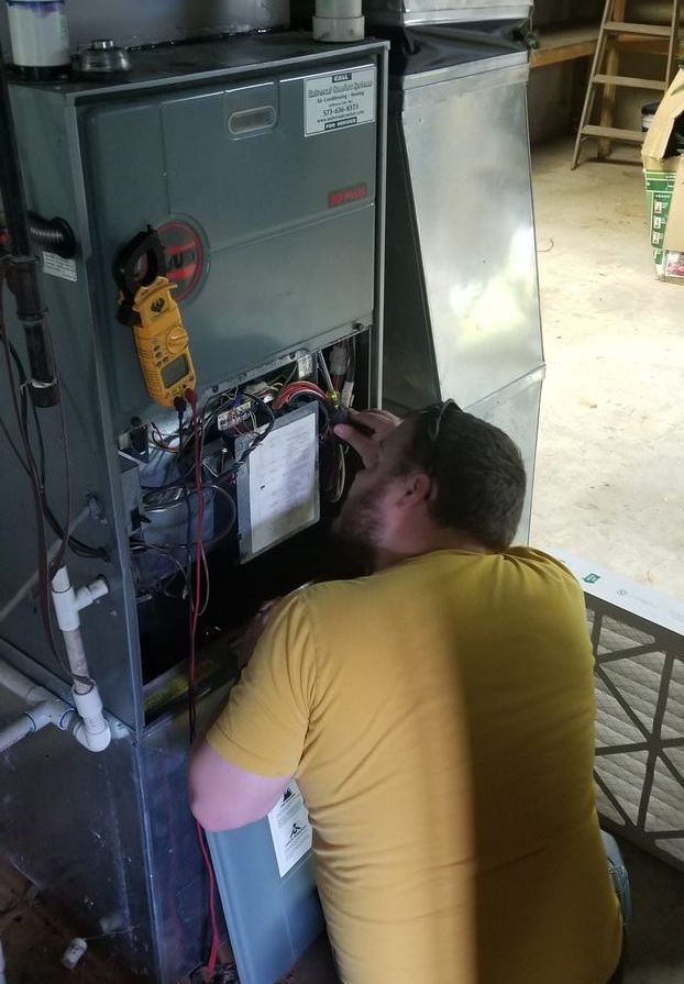 A man in a yellow shirt is working on a heating system.