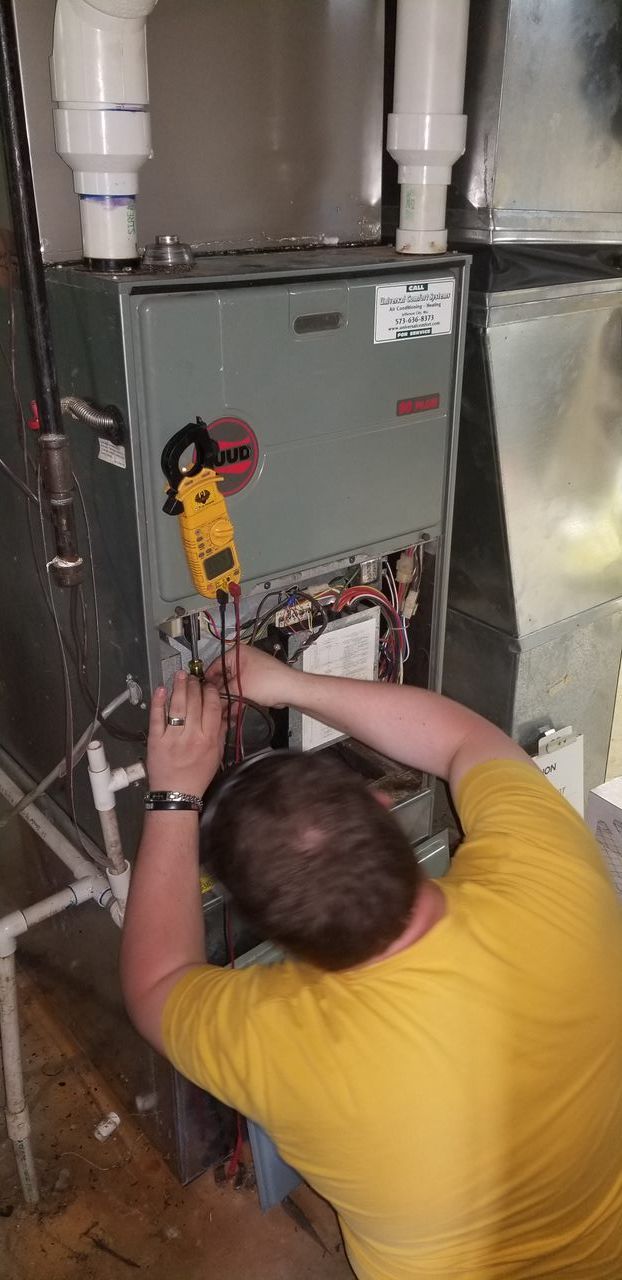 A man in a yellow shirt is working on a heating system.