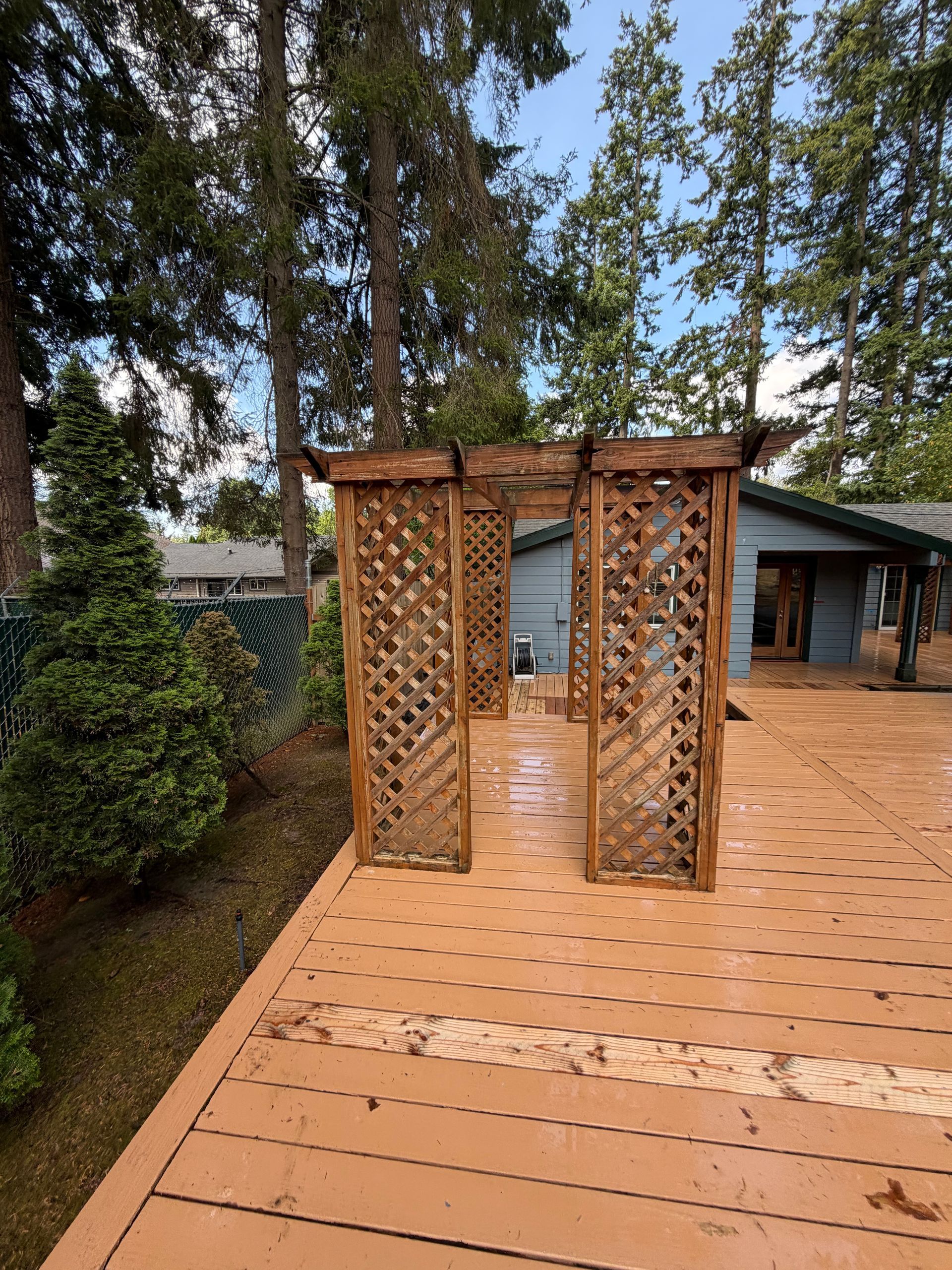 Wooden lattice garden archway on a deck, surrounded by trees and greenery