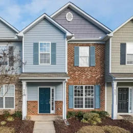 Row of townhouses with varying siding colors: blue, brick, and green.