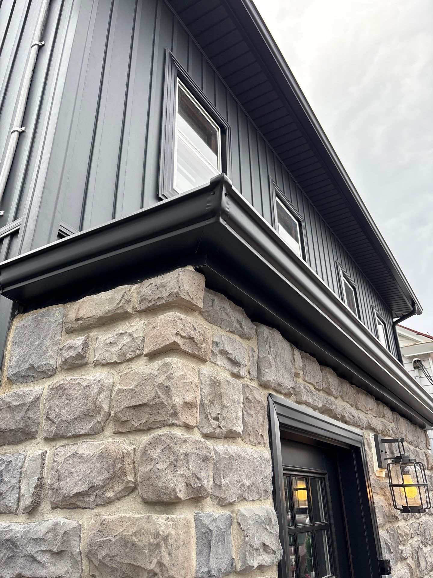 Stone and black metal exterior corner with a window and lantern above a doorway