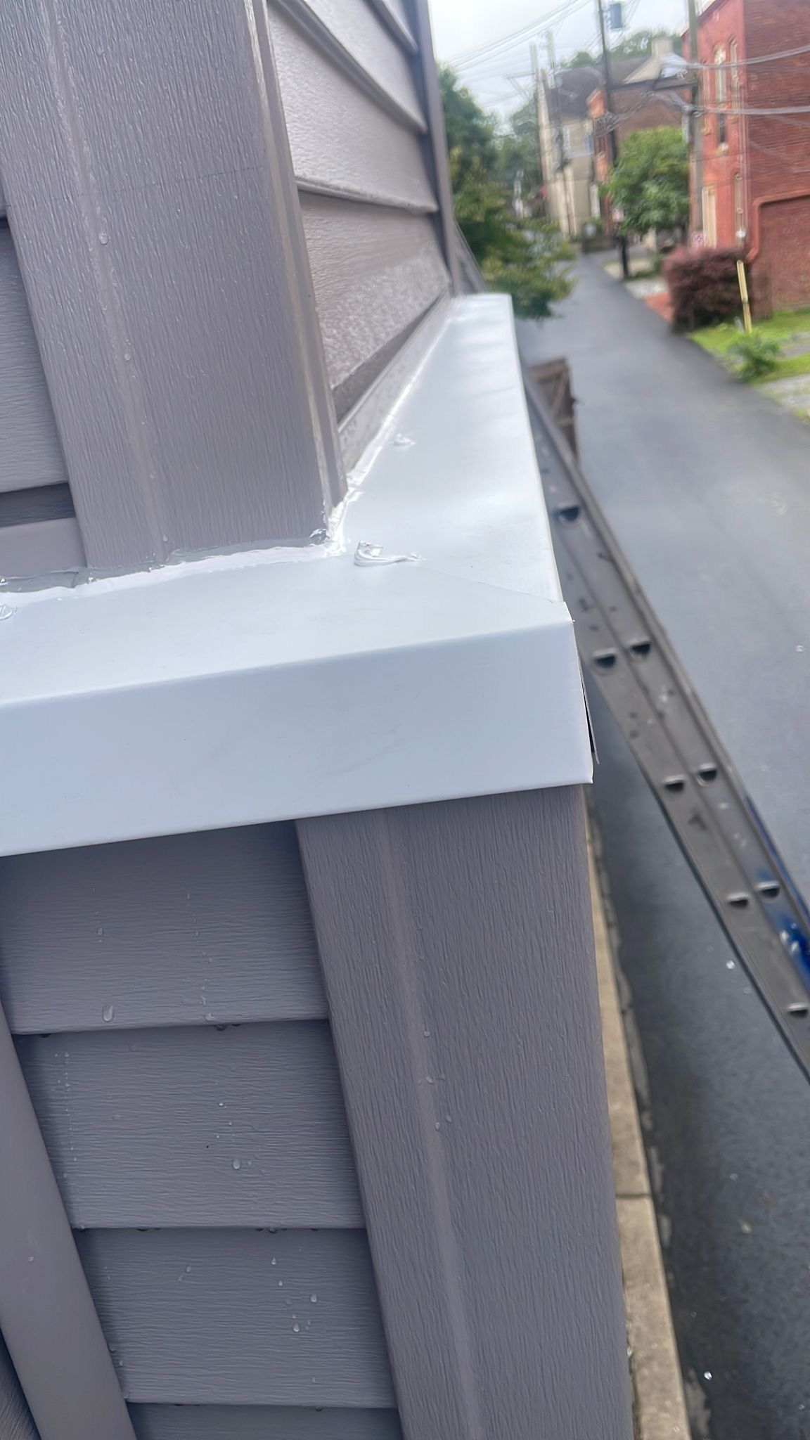 Gray siding and white trim on a building's exterior, overlooking an alley.