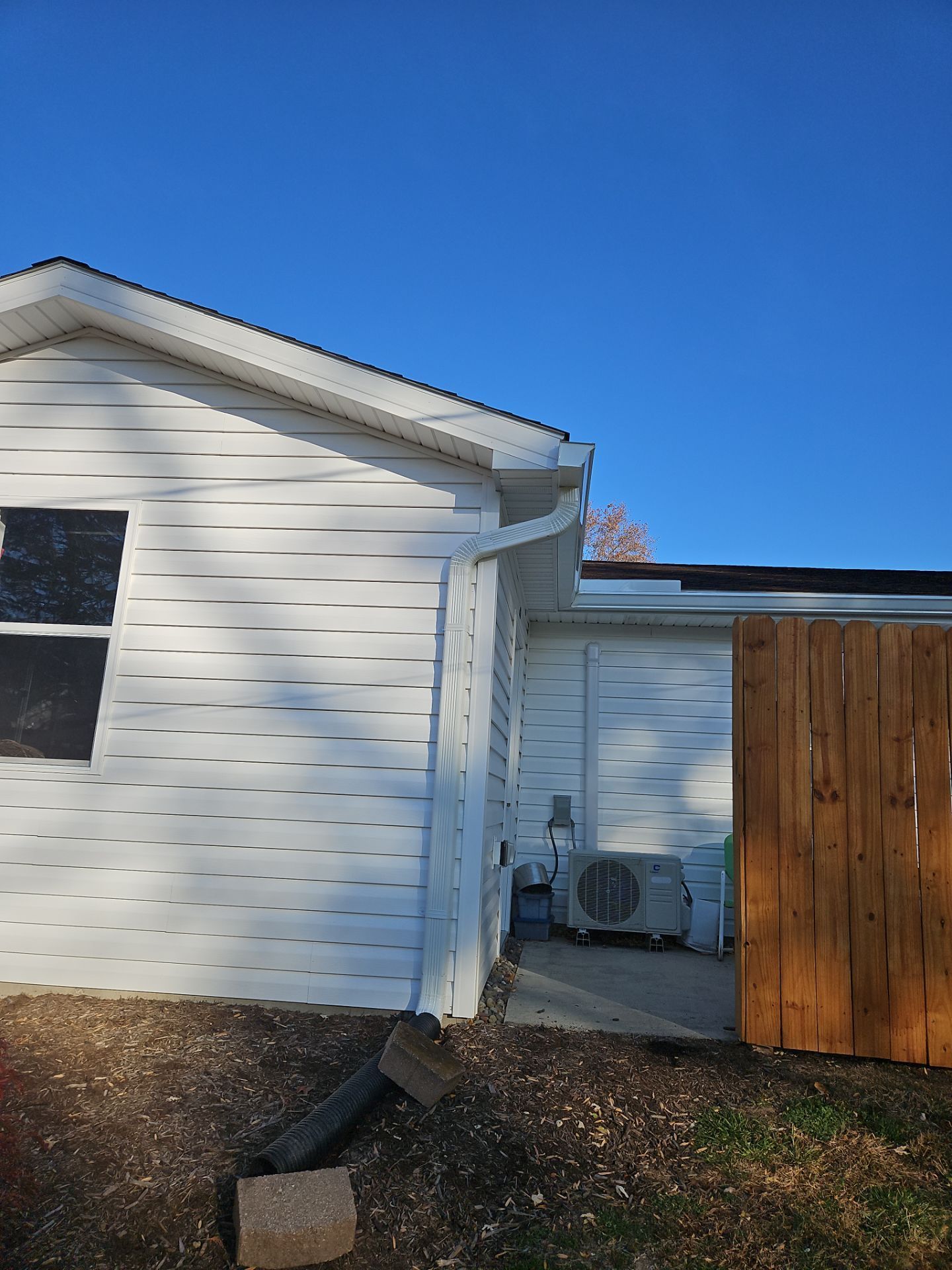 White house exterior with a wooden gate, side patio, and blue sky