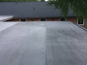 Black asphalt roof with a contrasting clean section, building background.