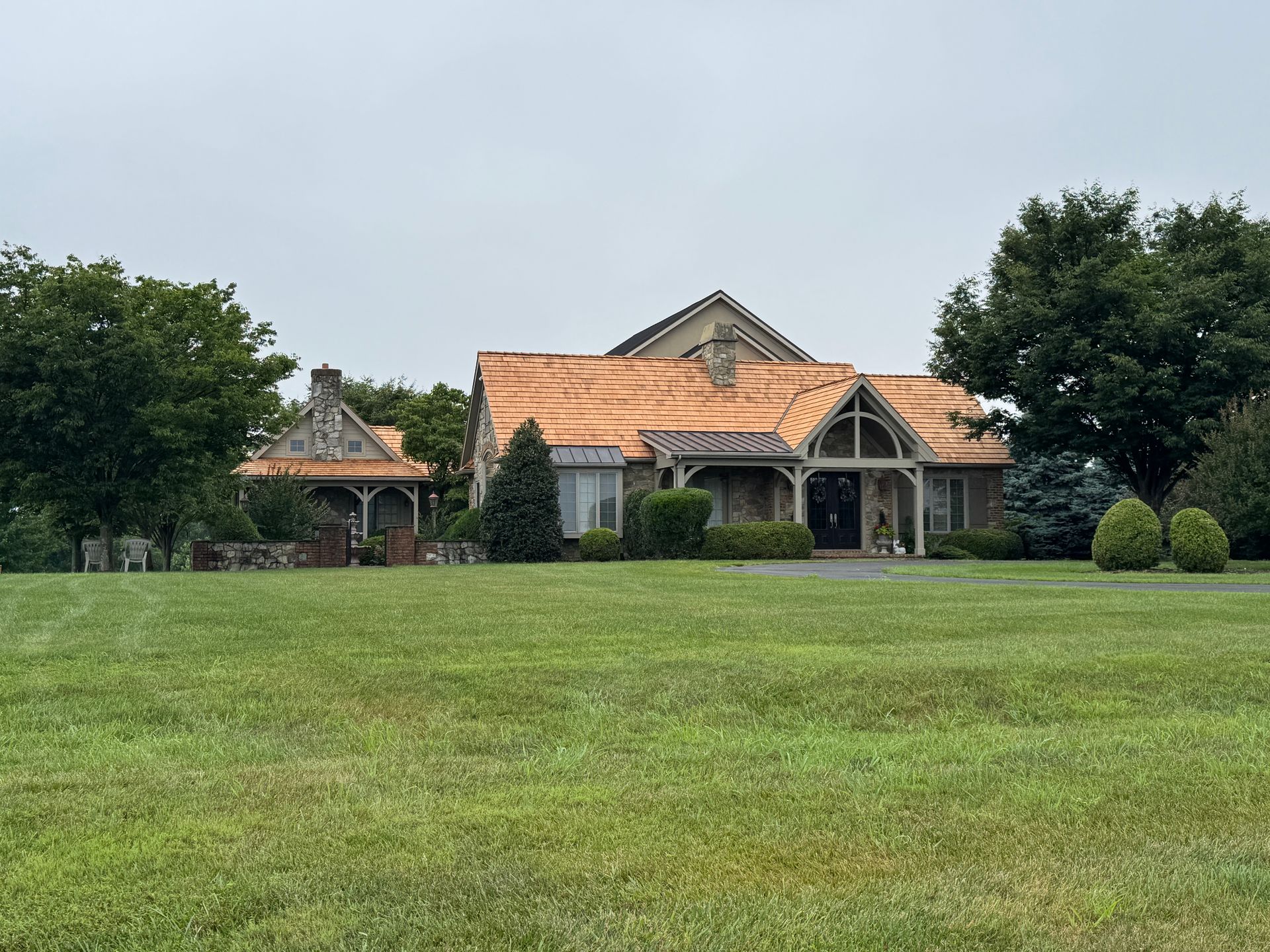 Large house with a terracotta roof behind a wide green lawn and trees