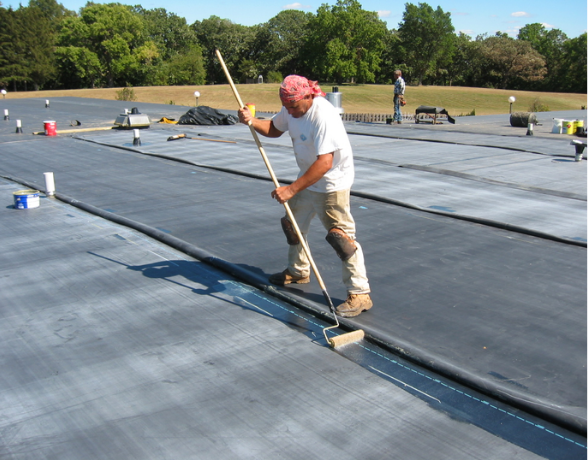 Joyland worker smoothing black EPDM membrane on a flat roof