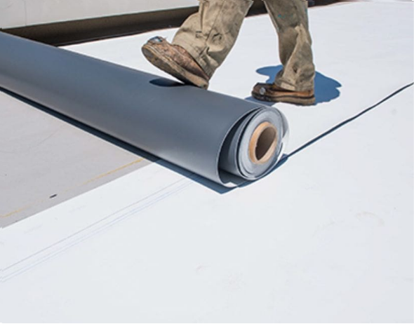 Joyland crew unrolling a gray TPO membrane on a commercial flat roof