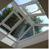 Skylight with geometric pane design, white frame, blue sky visible, trees outside.