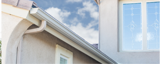 Exterior of a house with a gutter, window, and a cloudy sky.