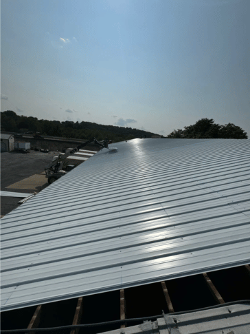 White metal corrugated roof on a building, under a bright blue sky.