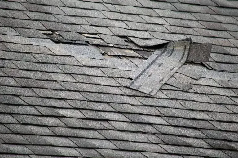 Damaged asphalt shingle roof with missing and torn shingles.