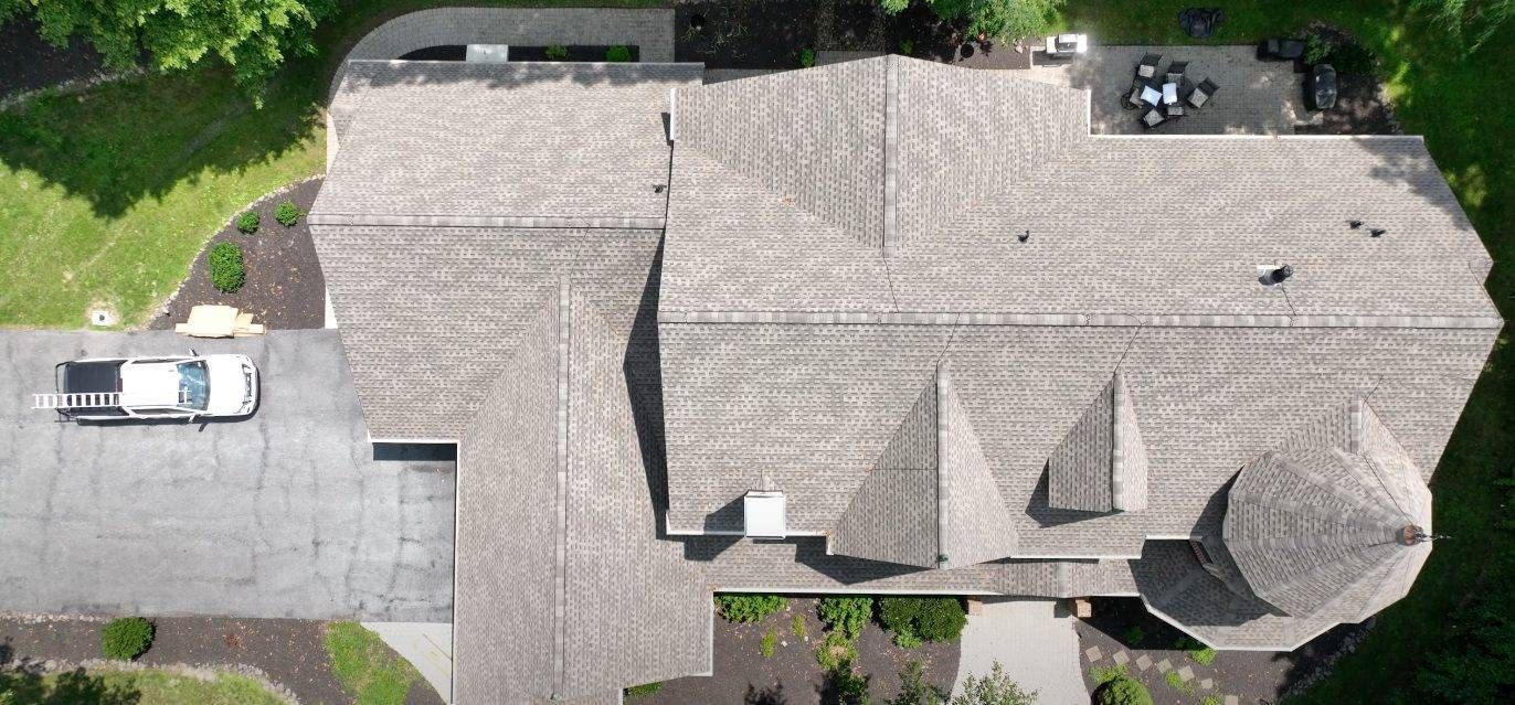 Overhead view of a house with a car parked in the driveway and a patio with furniture.