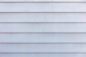 Horizontal rows of light blue siding, weathered texture.