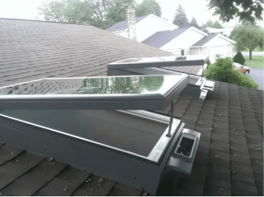 Three open skylights on a dark shingle roof, grey frames, partially open.