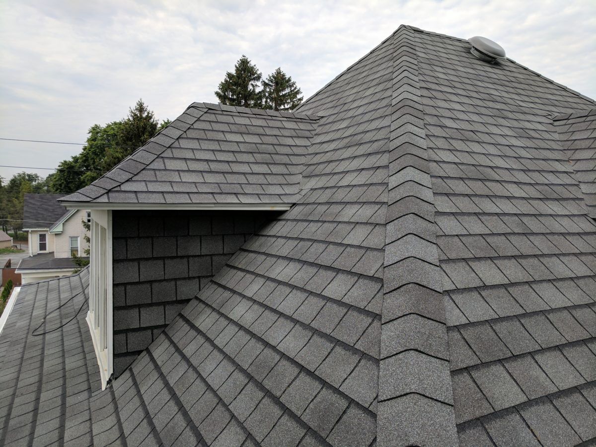 Brick house with gray slate roof, ivy climbing the walls, black-framed windows, and a green awning.