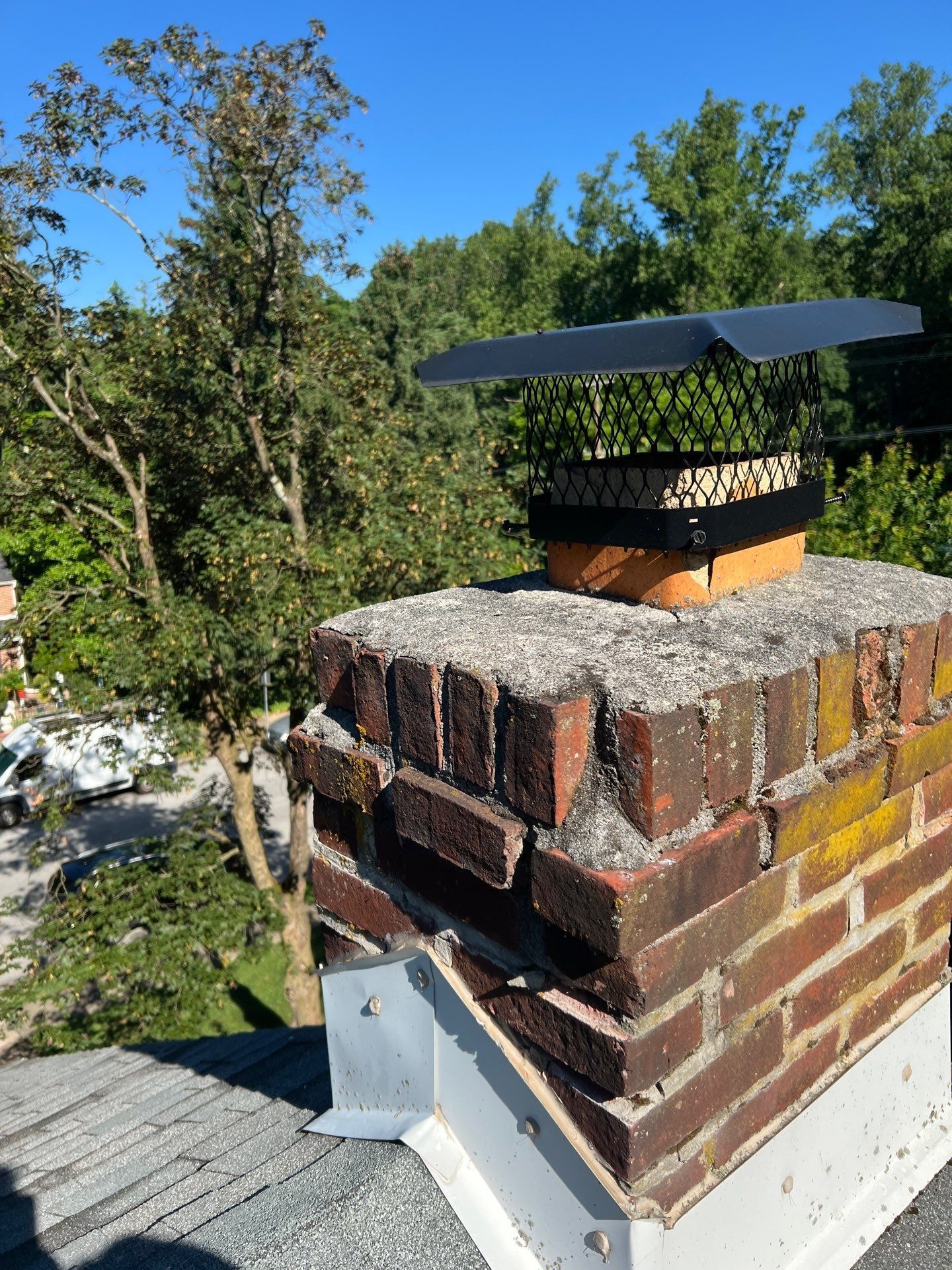Brick chimney with metal flashing and protective cap on an asphalt shingle roof on Ashwood Road in Springfield PA