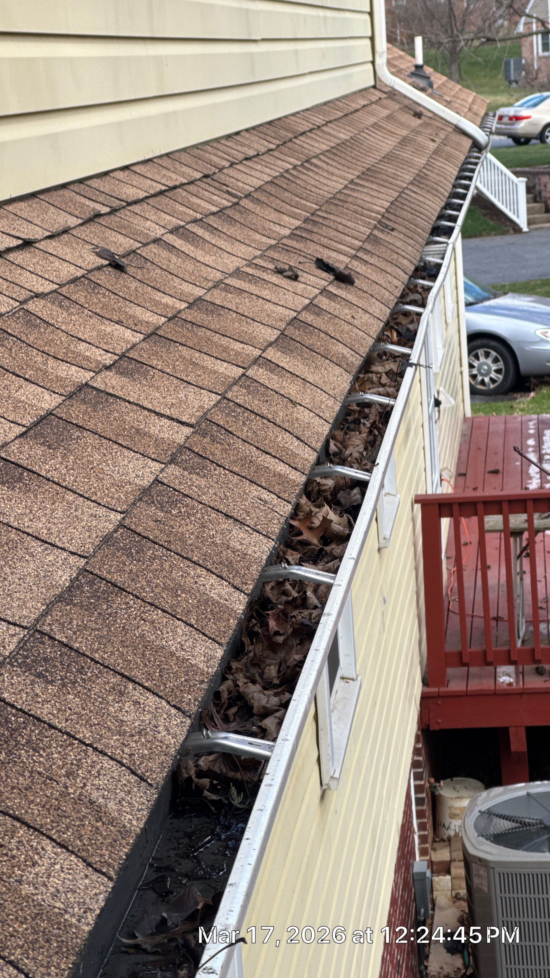 Debris-filled gutter system along an asphalt shingle roof during a roof and gutter inspection on Speckled Drive in East Petersburg, PA.