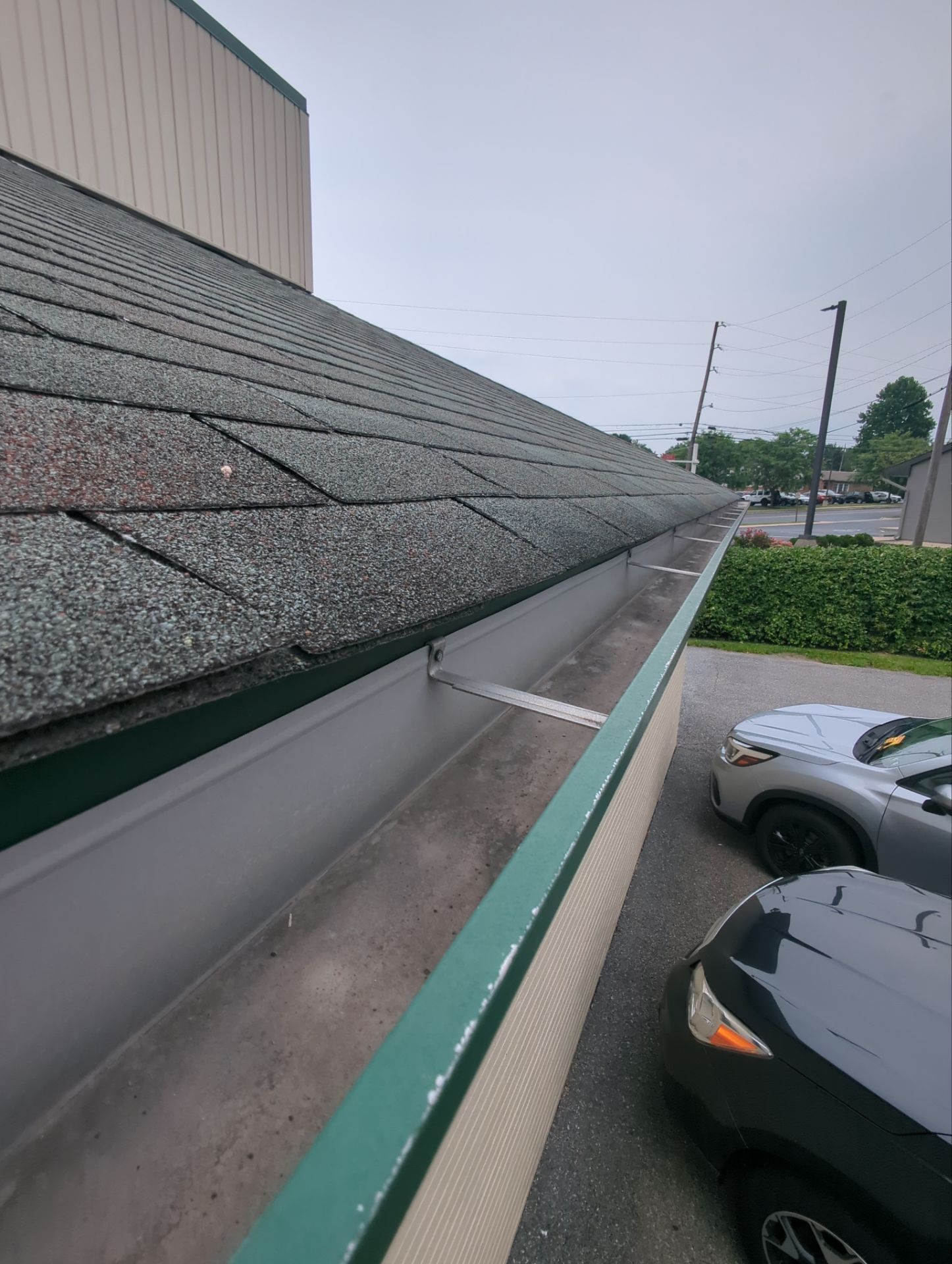 Commercial roofing and gutter system inspection on Main Street in East Petersburg, PA showing seamless gutters and asphalt shingles designed for proper water drainage and roof protection.