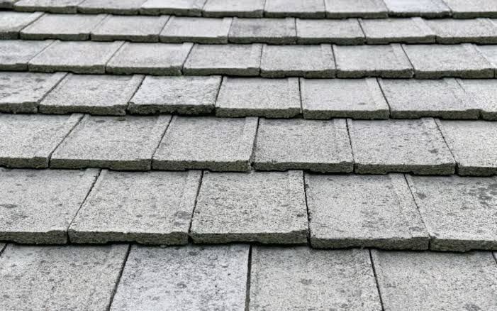 Close-up of gray concrete shingles on a sloped roof, showing layered rows and weathered texture