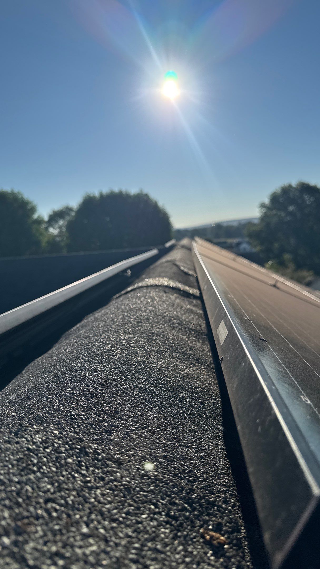 Close-up view of roof-mounted solar panel rails installed along the roof ridge on an asphalt shingle roof before solar panels are attached.