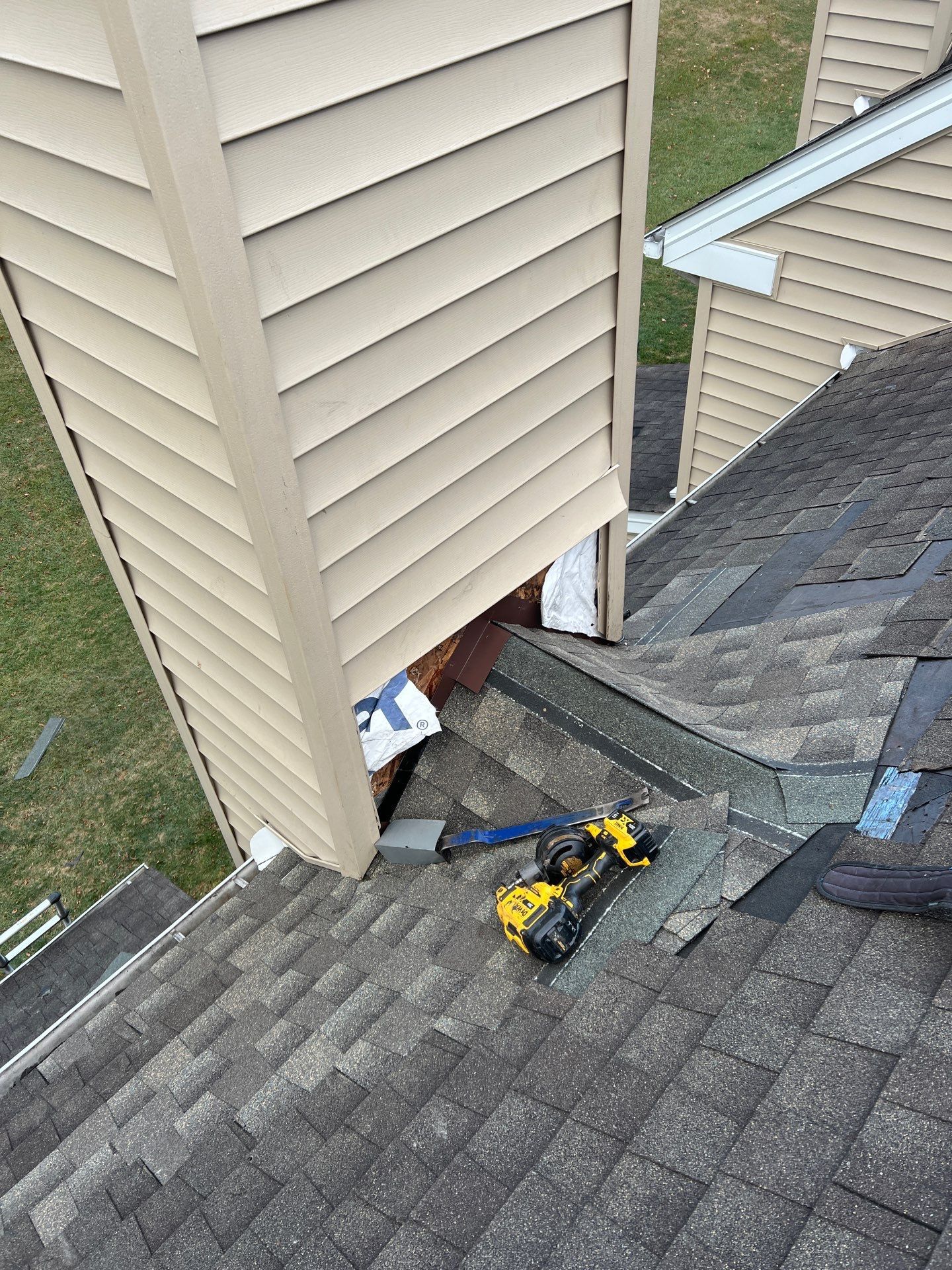 Roof repair in progress around a chimney sidewall with new flashing and asphalt shingles on Dover Court in Morgantown, PA.