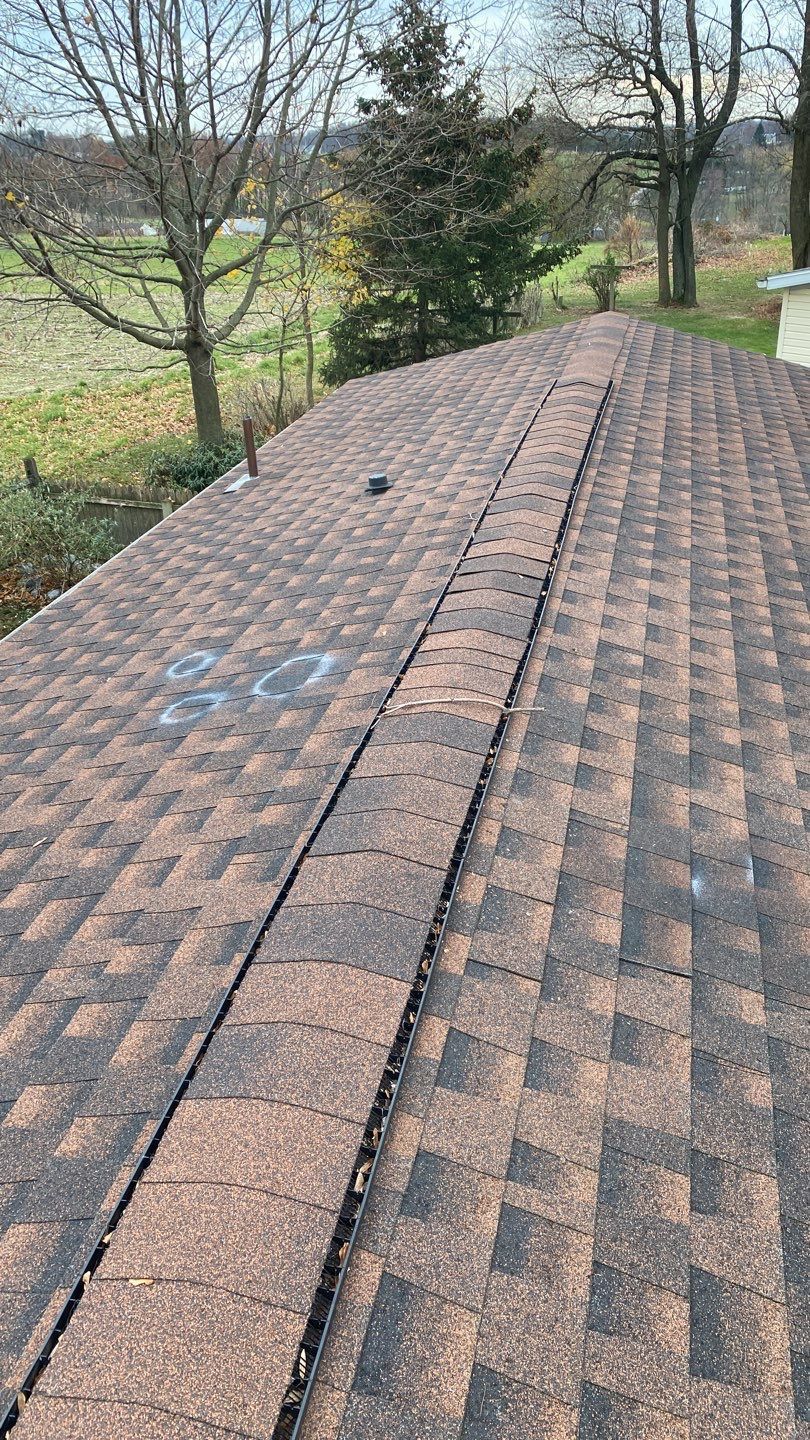 Asphalt shingle roof on Dusk Street in Quarryville, PA showing an aging ridge vent with debris buildup along the roof peak during a roof replacement inspection.