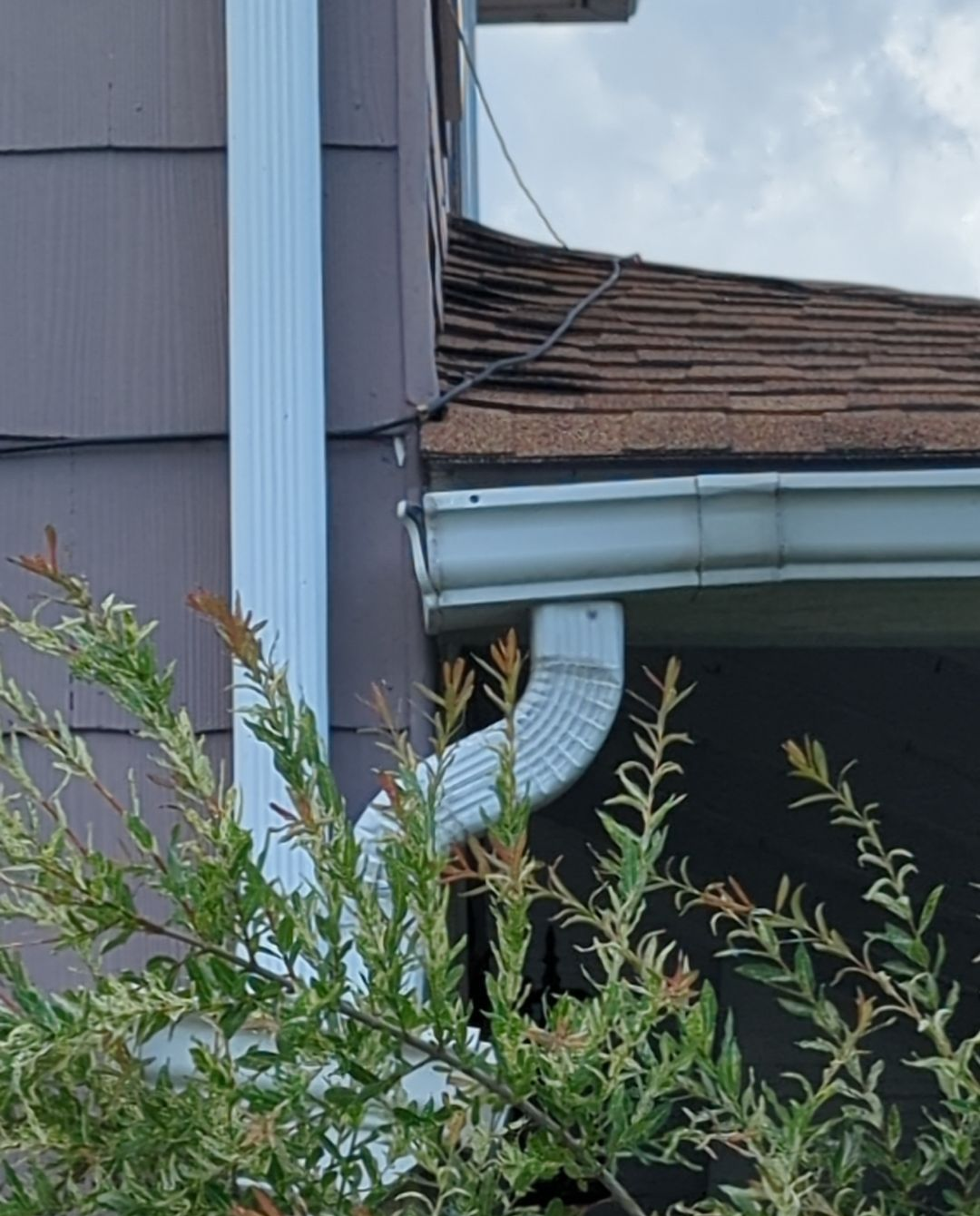 Close-up of a residential gutter, downspout, and asphalt shingle roof showing the roof edge and drainage system on a home in Quarryville, PA.