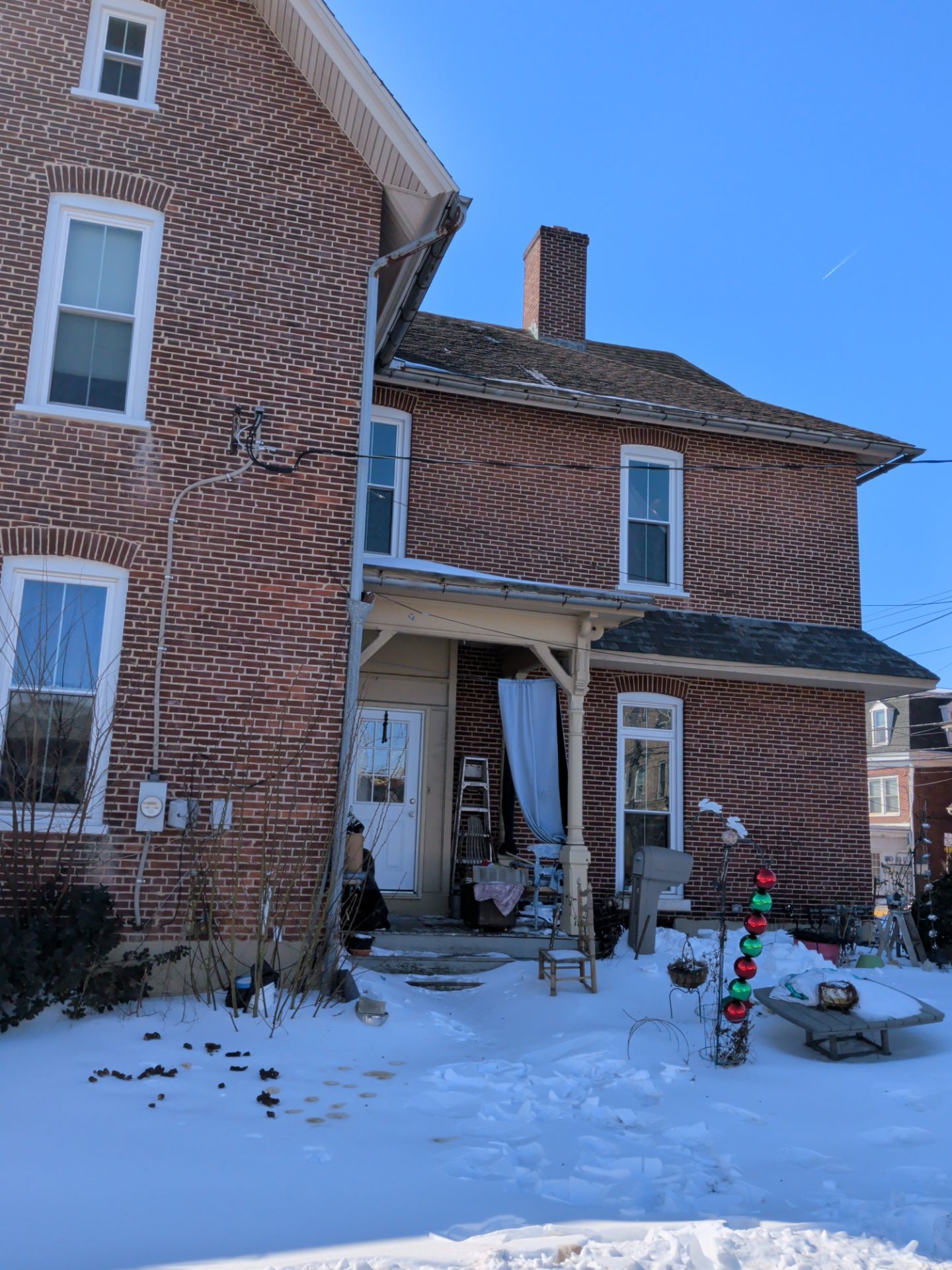 Brick home on East Main Street with an aging asphalt shingle roof showing signs of wear during a residential roof replacement evaluation.