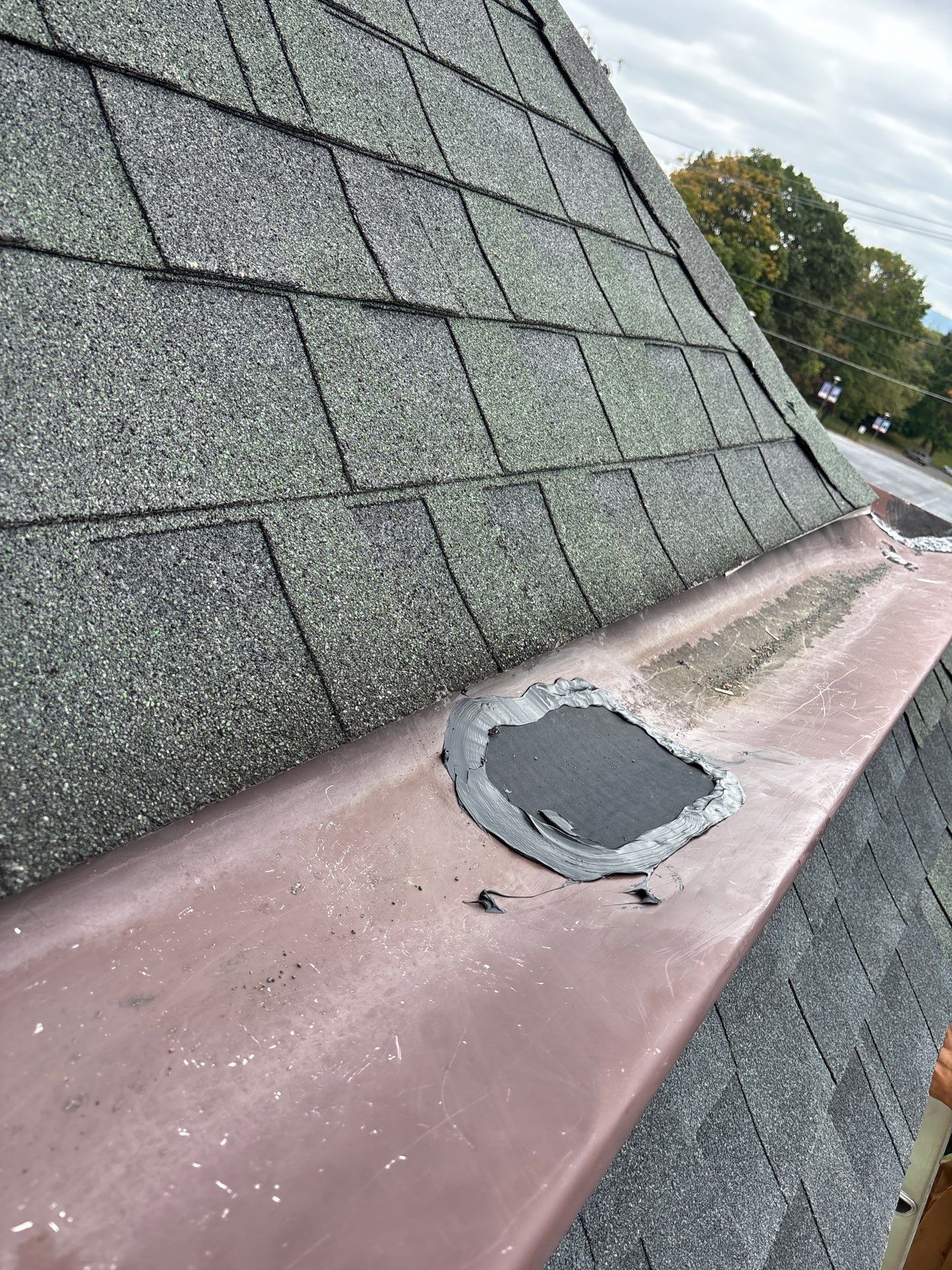 Roof flashing repair with sealant applied along an asphalt shingle roof on East Main Street in Kutztown, PA.