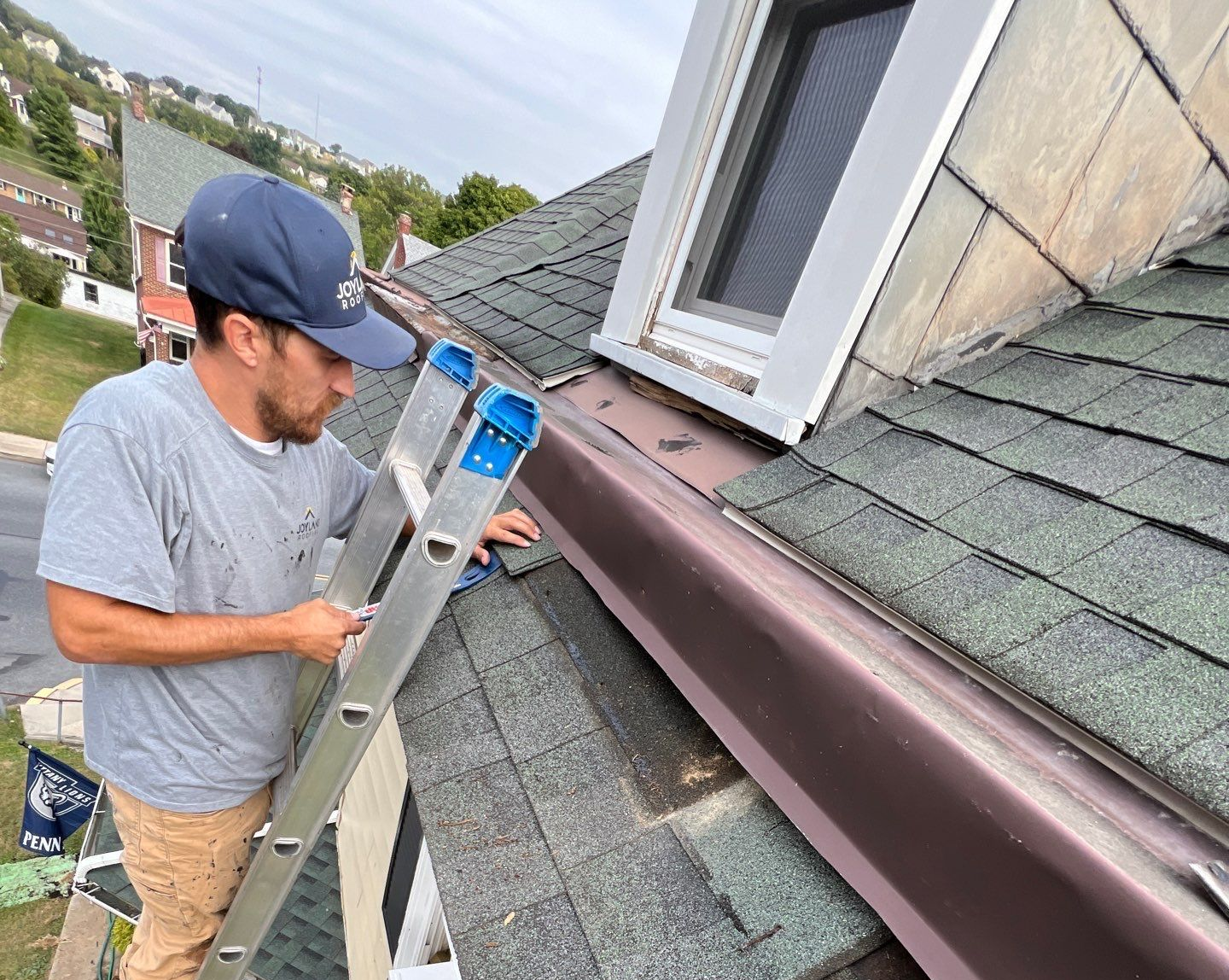 Roofing technician repairing step flashing around a dormer during a roof repair process on East Main Street in Kutztown, PA.